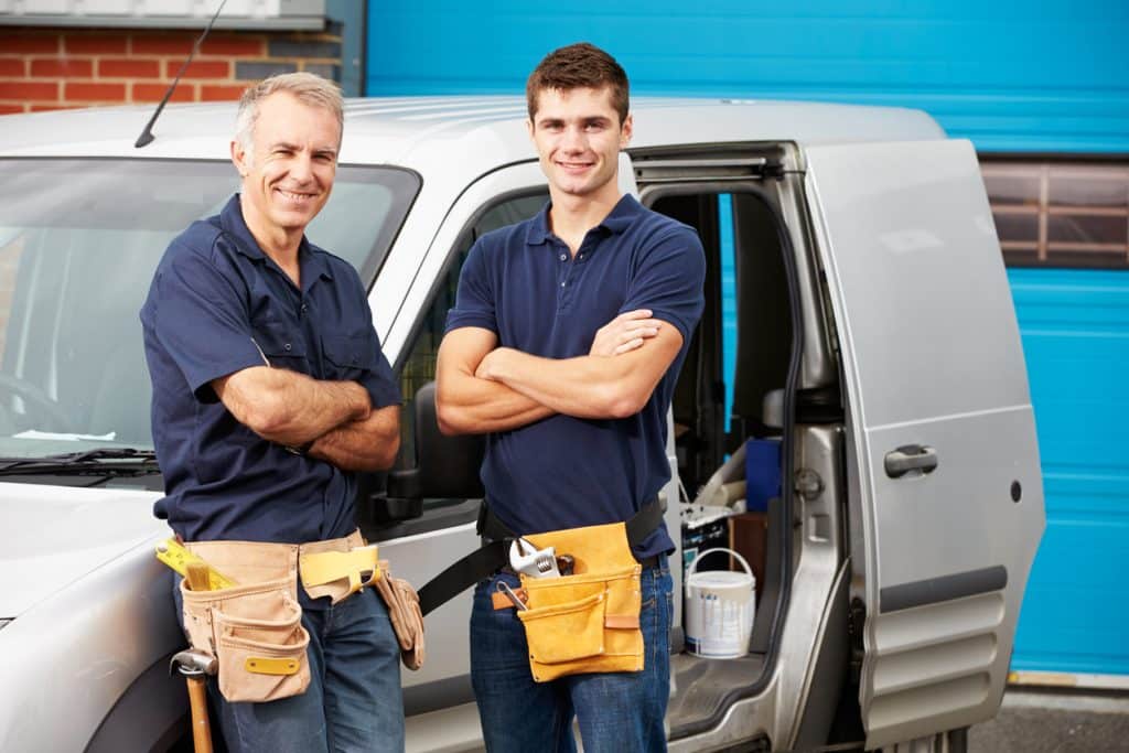 Workers In Family Business Standing Next To Van Smiling At Camera